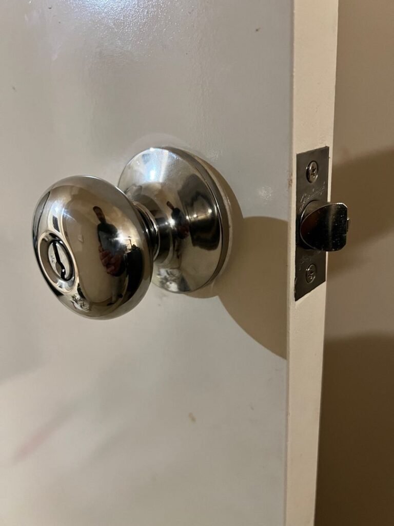 Close-up of a metallic keyed knobset on a white door.
