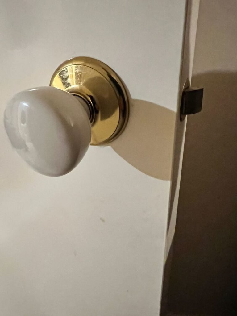 Close-up of a newly installed passage knob with a brass base and ceramic knob on a white door.