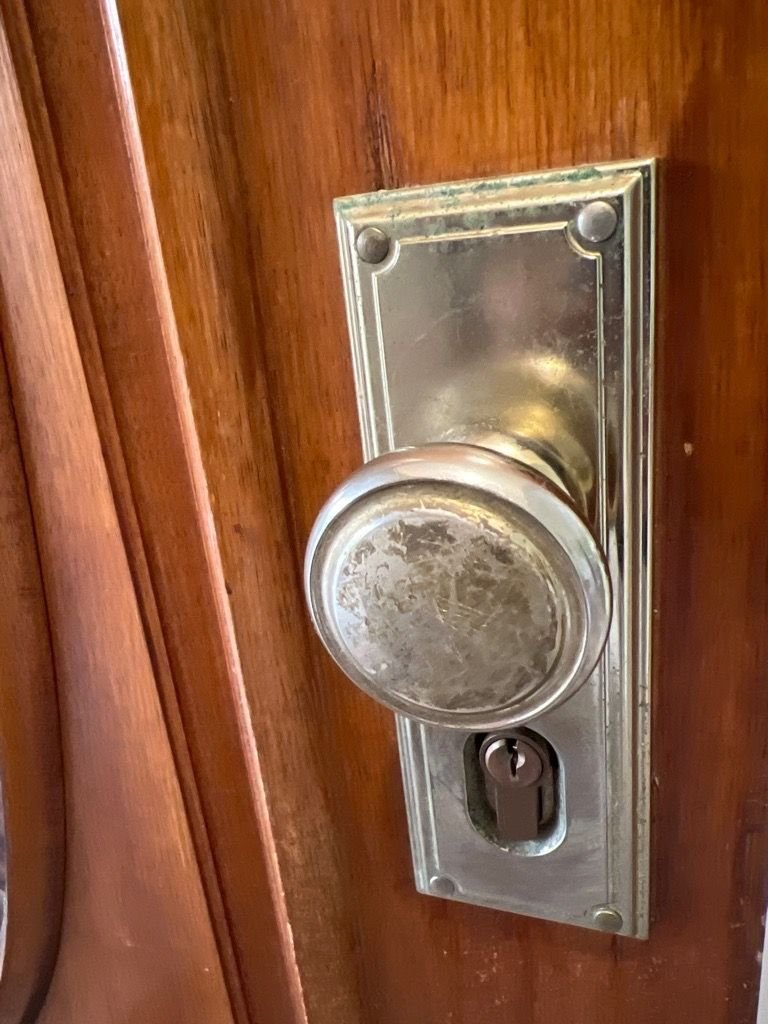 Close-up view of a Gainsborough Trilock installed on a wooden door, featuring a round doorknob and keyhole.