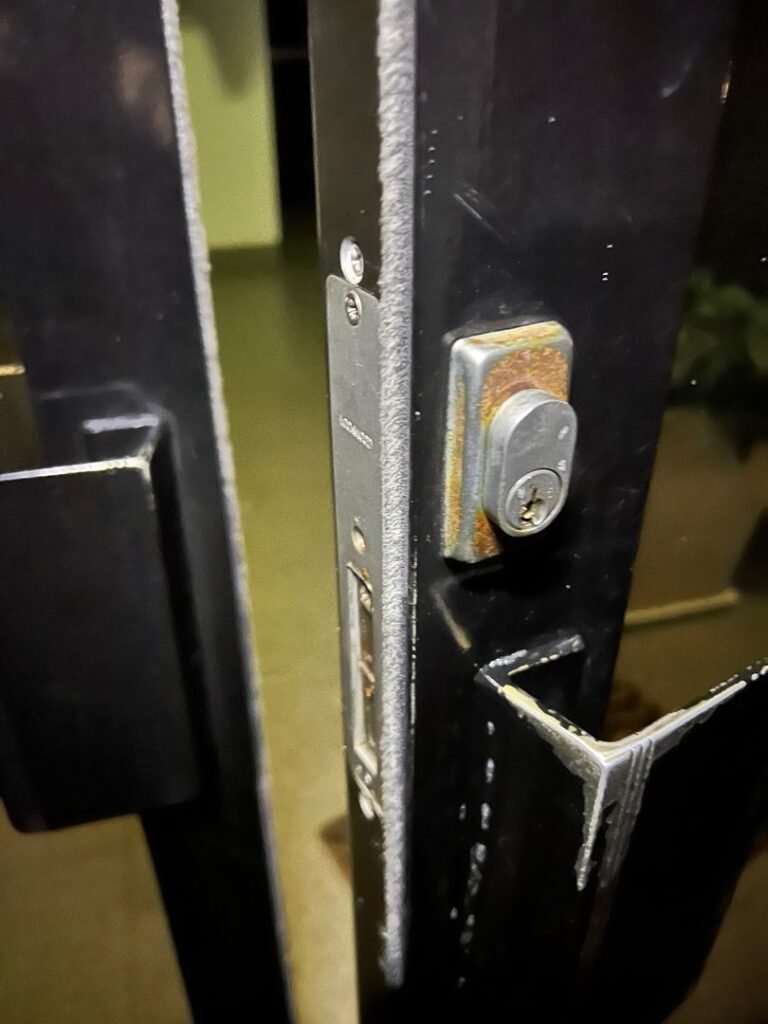 Close-up view of a key stuck in an office door lock with visible rust and wear.