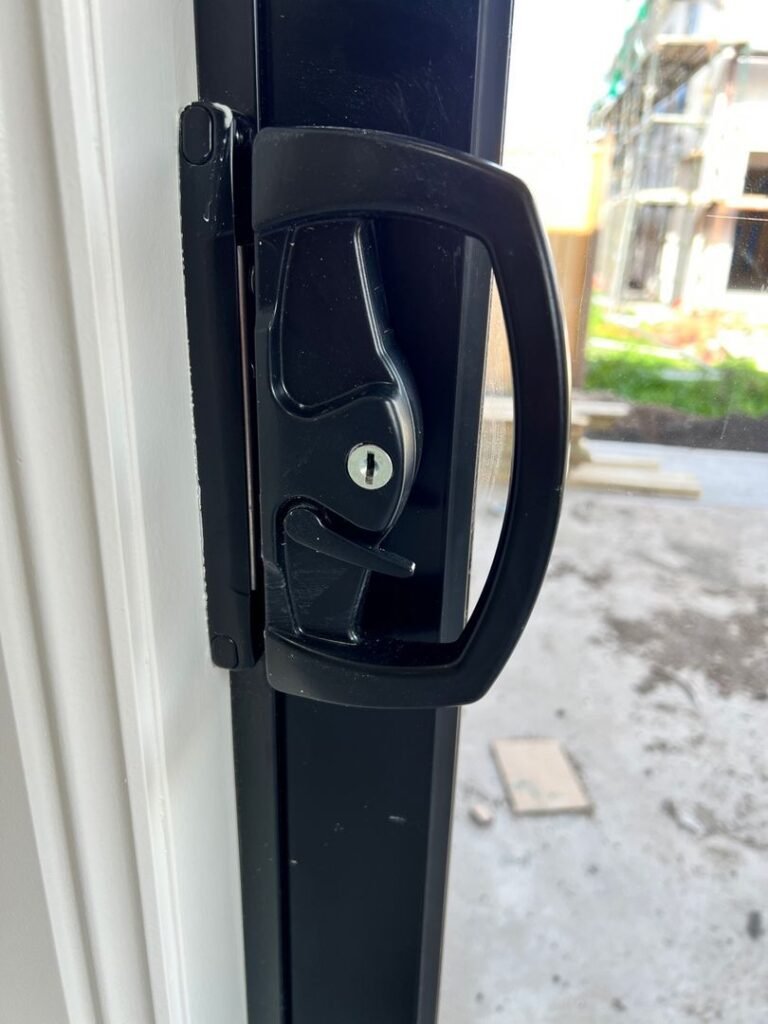 Close-up of a newly installed sliding door lock with a keyhole in a residential setting.