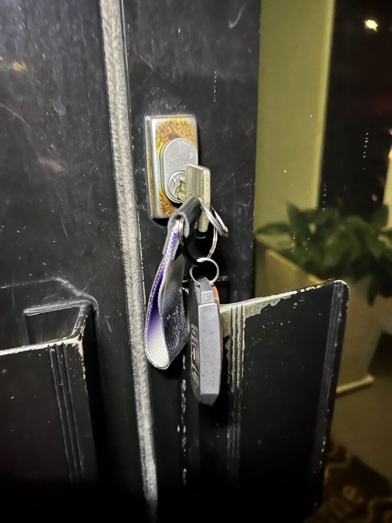Key stuck in a rusted lock on an office door with a keychain attached
