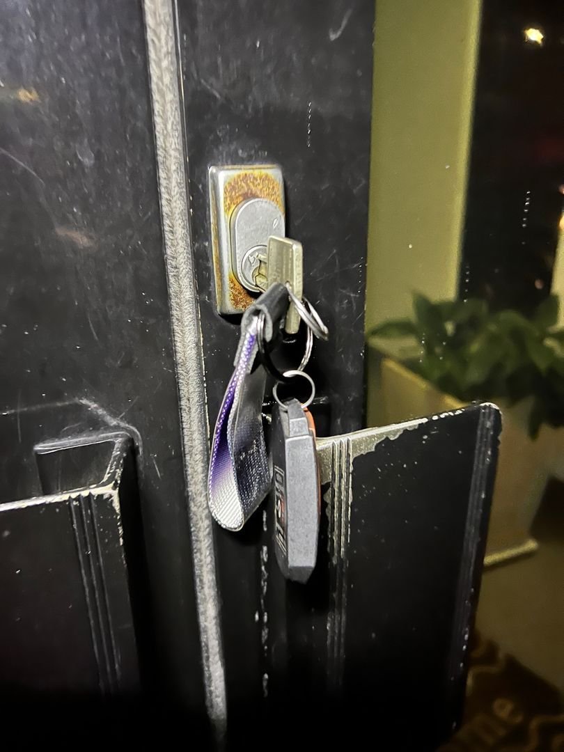 Key stuck in a rusted lock on an office door with a keychain attached