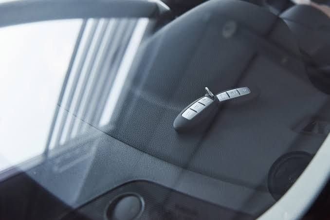 Car keys locked inside a vehicle, placed on the dashboard and viewed through the windshield.