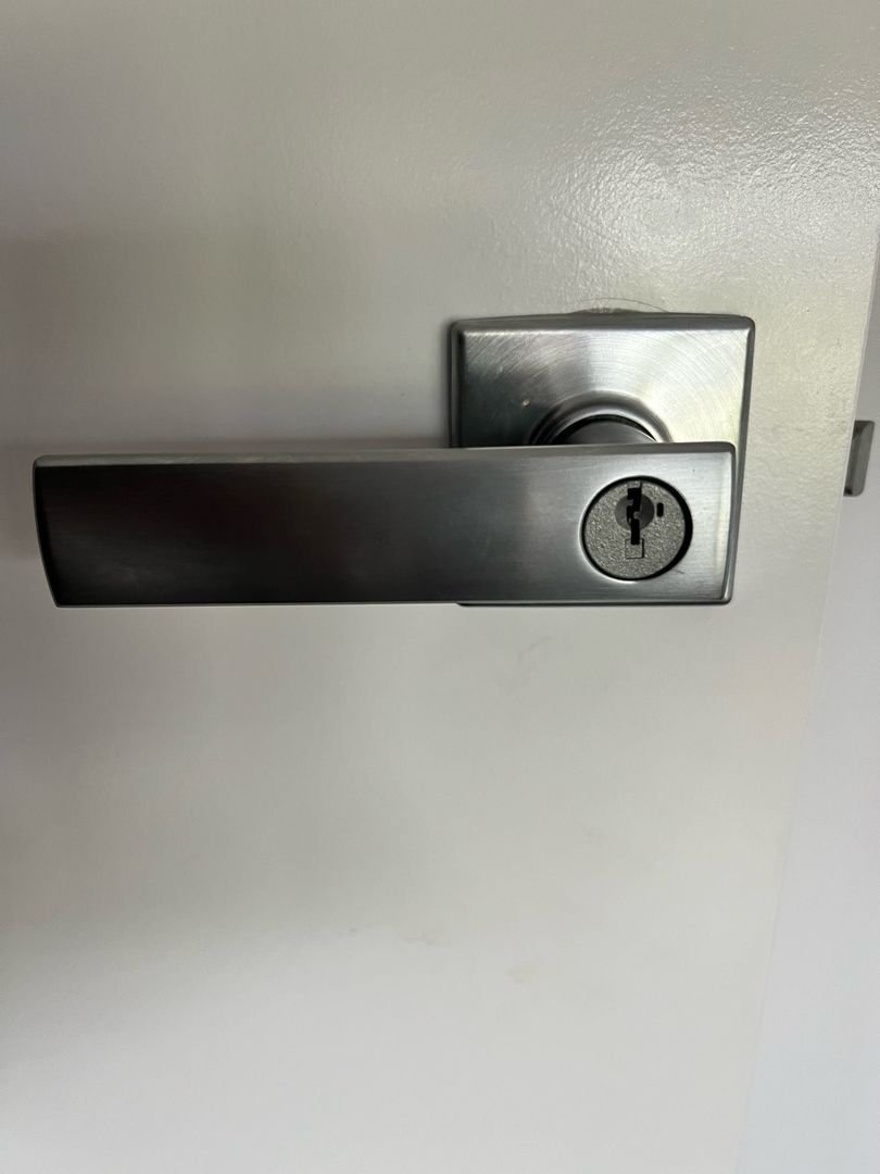 Close-up of a newly installed modern metallic door handle with keyhole on a white door.