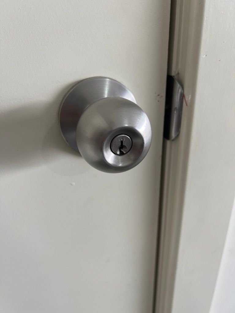 Close-up of a stainless steel door knob with keyhole on a white door.