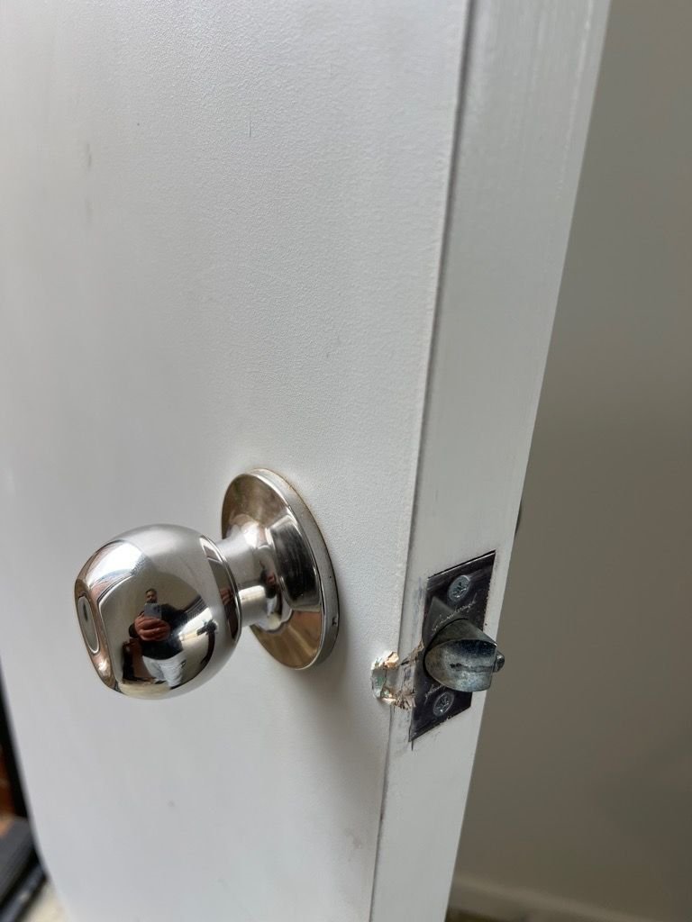 Close-up of new deadbolt installation on a white door with a metallic doorknob.