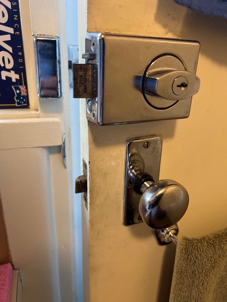 Close-up view of a door with a new metallic deadbolt lock and round door knob.