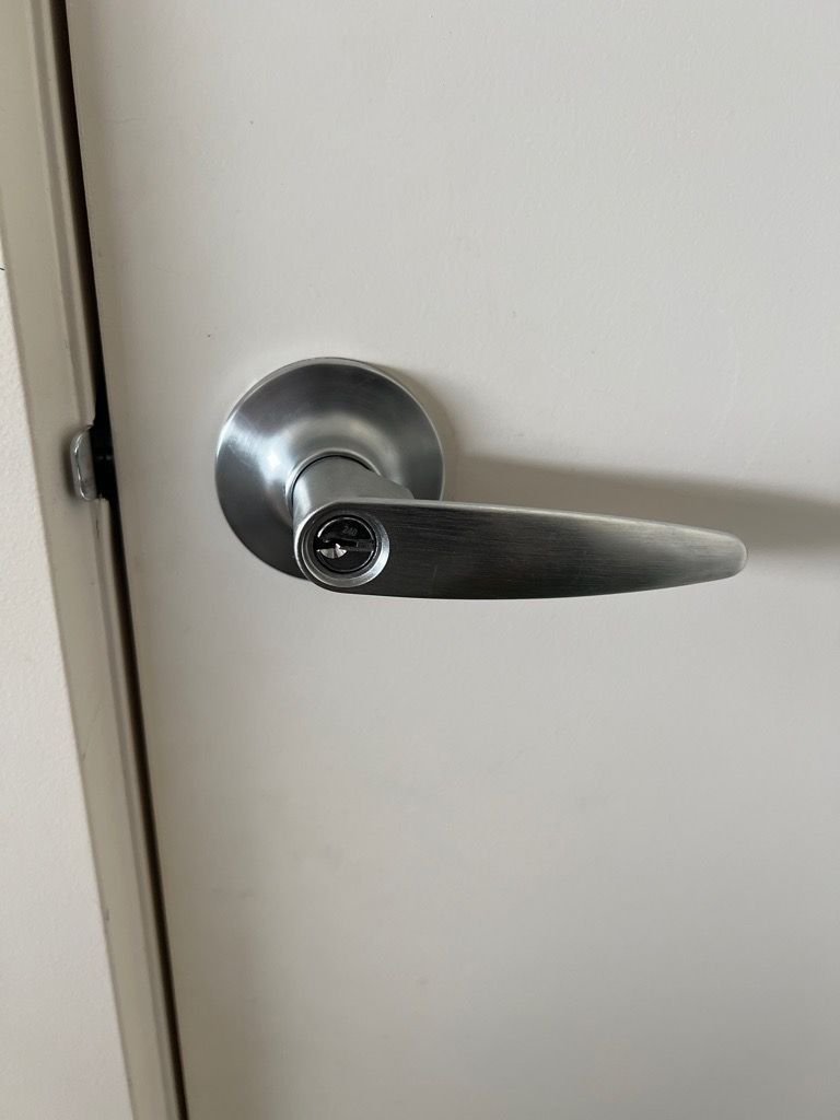 Close-up of a metal door handle with a keyhole on a white door