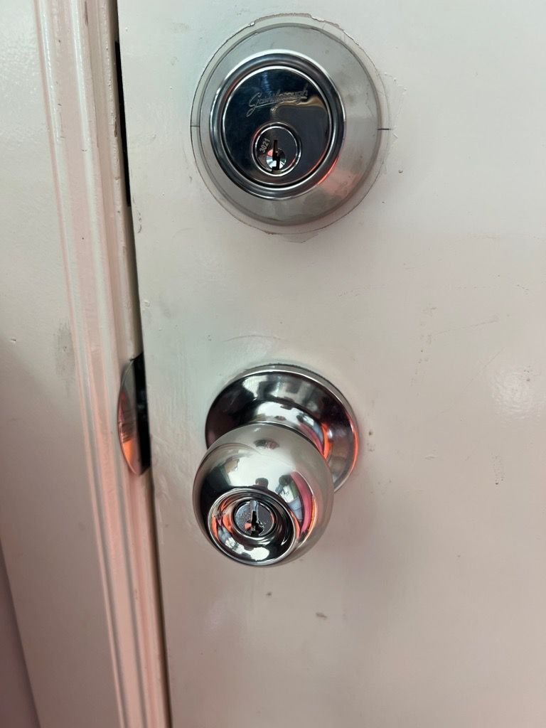 Newly installed chrome Gainsborough deadbolt and knobset on a white door.