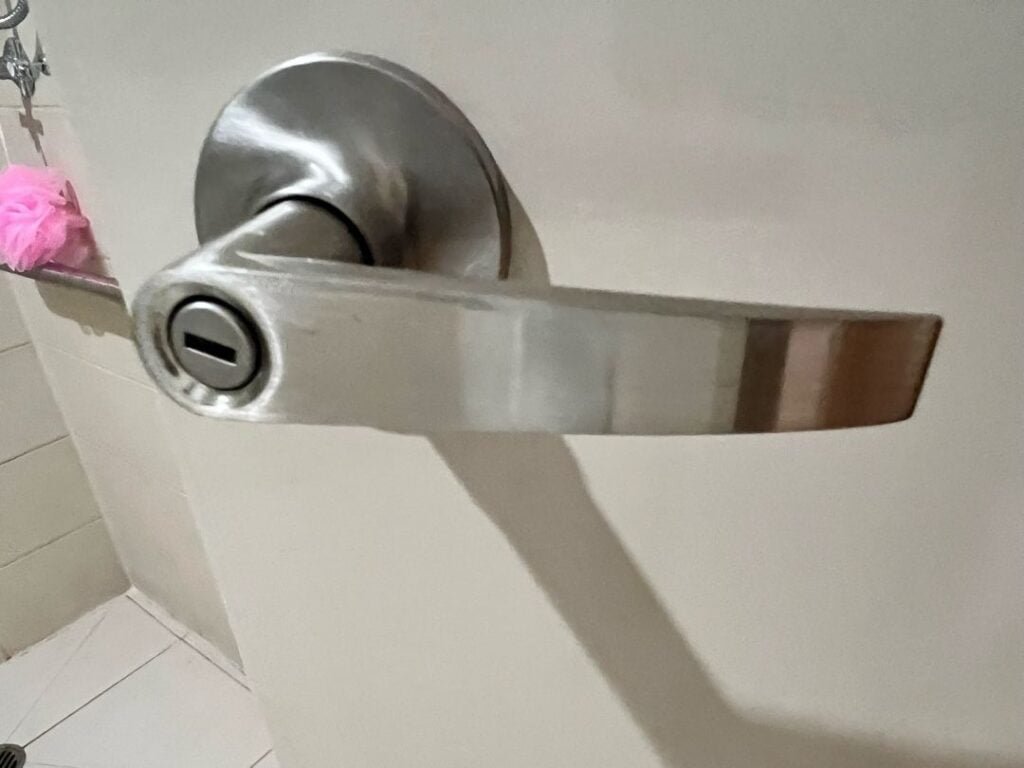 Close-up of a metallic privacy lever handle with keyhole on bathroom door