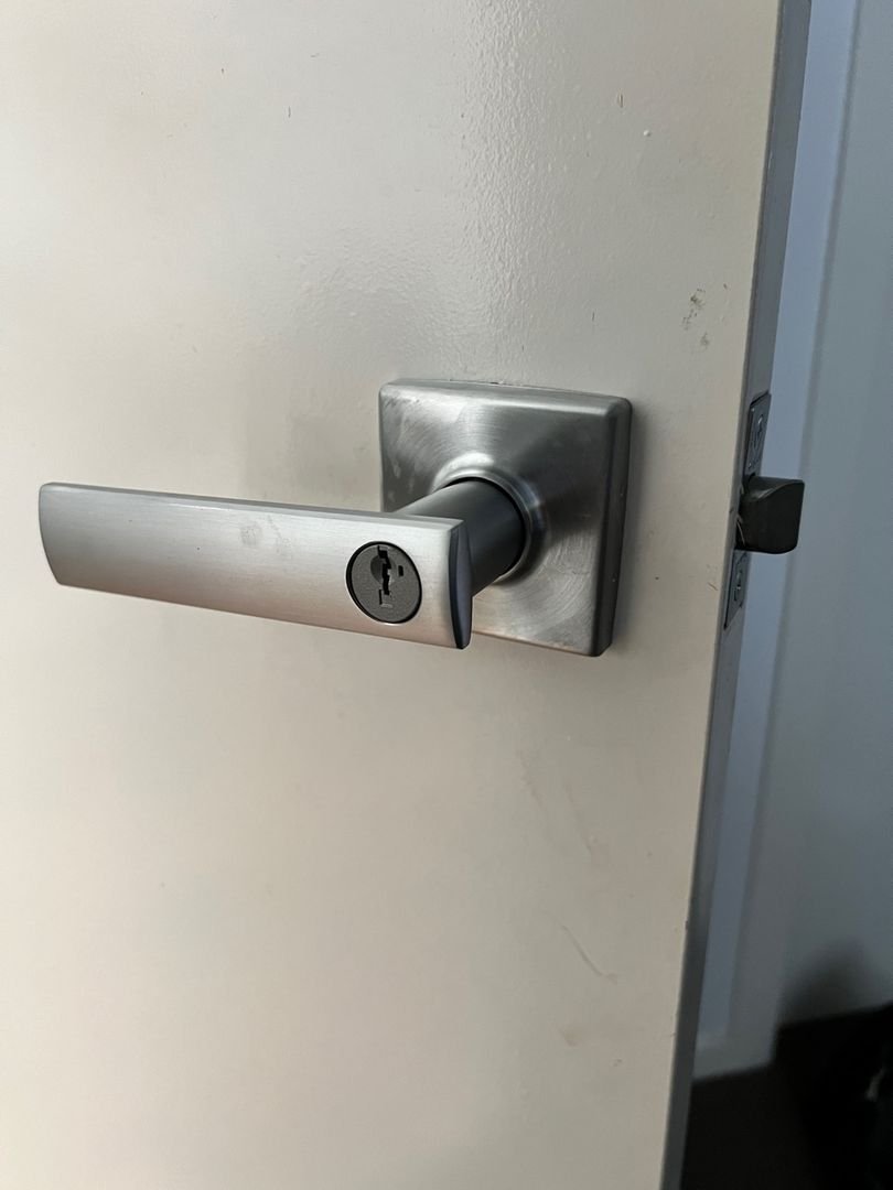 Newly installed Kwikset lever handle on a white door