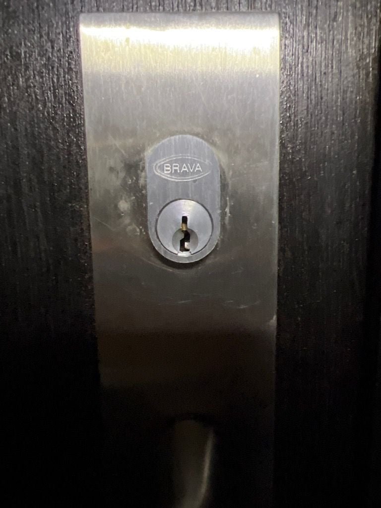 Close-up image of a BRAVA door lock on a dark-colored door.