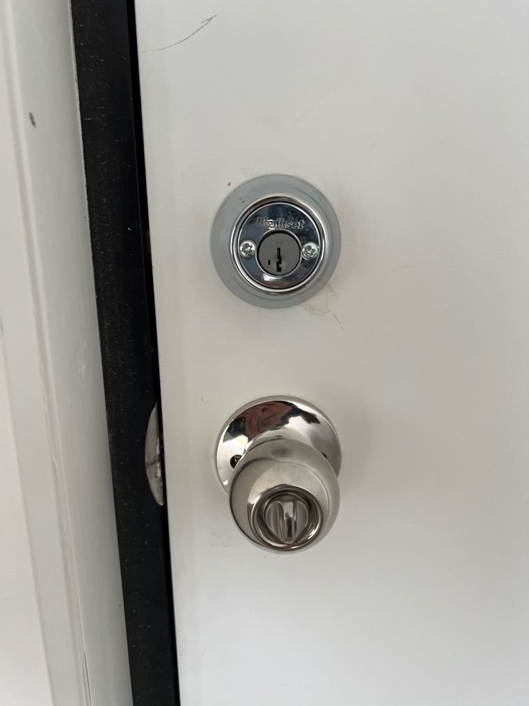 Newly installed Kwikset deadbolt and door handle on a white entry door.