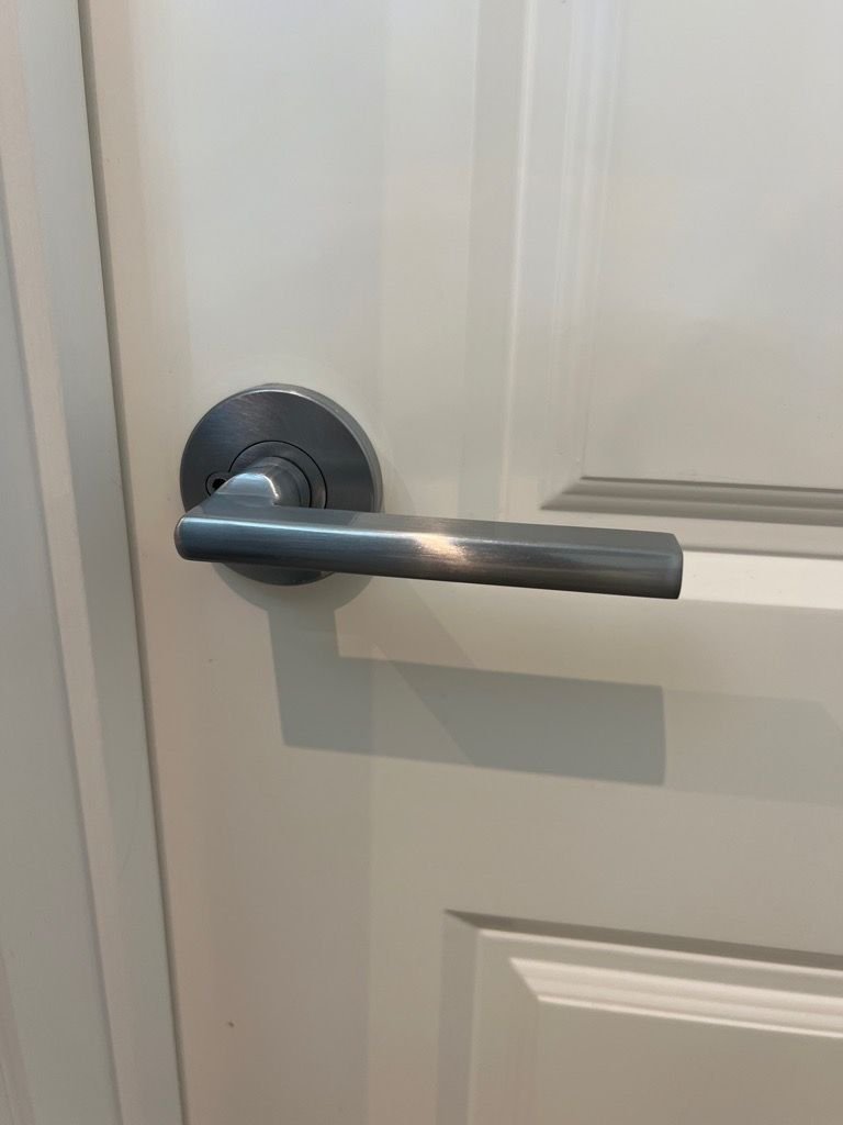 Close-up view of a metallic lever door handle on a white door.